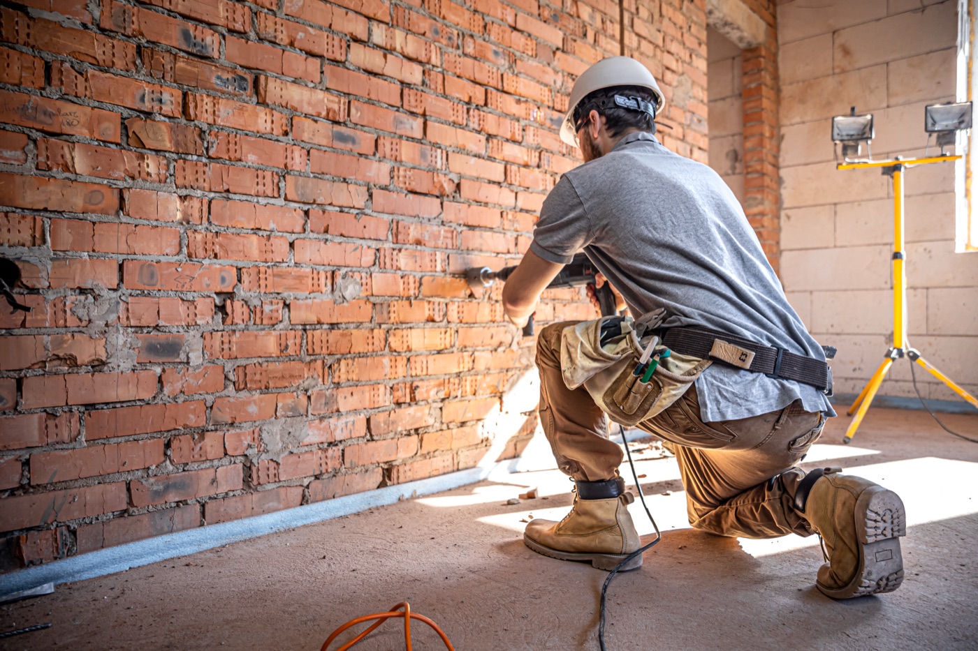 Bauarbeiter bohrt mit einem Bohrhammer eine Ziegelwand auf einer Baustelle